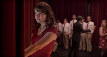 Movie still from “CODA” (2021), directed by Sian Heder – A woman in a red dress in front of a group of people; Medium shot, Over the shoulder angle