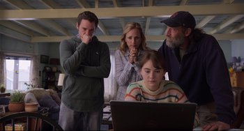 Movie still from “CODA” (2021), directed by Sian Heder – A group of people standing around a laptop computer; Medium shot, Over the shoulder angle