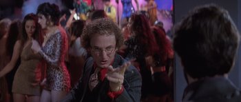 Movie still from “Carlito's Way” (1993), directed by Brian De Palma – A man in a suit and red bow tie is holding his hand out to the camera; Medium shot, Low angle