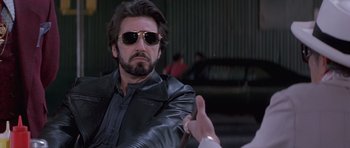 Movie still from “Carlito's Way” (1993), directed by Brian De Palma – A person wearing sunglasses and a leather jacket; Close Up shot, Over the shoulder angle