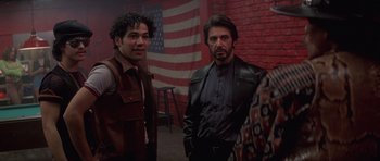 Movie still from “Carlito's Way” (1993), directed by Brian De Palma – Two men standing next to each other in front of an american flag; Medium shot, Over the shoulder angle