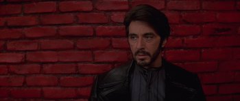 Movie still from “Carlito's Way” (1993), directed by Brian De Palma – A person wearing a leather jacket near a brick wall; Close Up shot, Low angle
