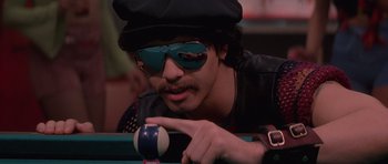 Movie still from “Carlito's Way” (1993), directed by Brian De Palma – A man wearing sunglasses and a hat is playing a game of pool; Close Up shot, Over the shoulder angle