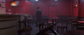 Movie still from “Carlito's Way” (1993), directed by Brian De Palma – A person standing in a room with chairs and tables; Wide shot, High angle