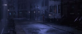 Movie still from “Carlito's Way” (1993), directed by Brian De Palma – A person with an umbrella is walking down the street at night; Extreme Wide shot, High angle