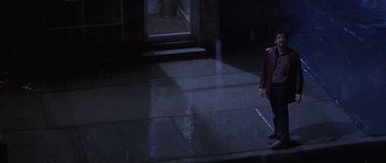 Movie still from “Carlito's Way” (1993), directed by Brian De Palma – A person standing on a sidewalk in the rain; Wide shot, High angle