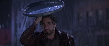 Movie still from “Carlito's Way” (1993), directed by Brian De Palma – A man holding a metal plate on his head; Close Up shot, Low angle