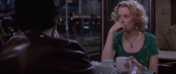 Movie still from “Carlito's Way” (1993), directed by Brian De Palma – A woman sitting at a table with a cup of coffee; Medium shot, Over the shoulder angle
