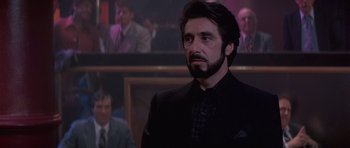Movie still from “Carlito's Way” (1993), directed by Brian De Palma – A man in a suit and tie in front of a group of people; Close Up shot, Low angle