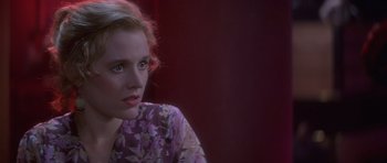 Movie still from “Carlito's Way” (1993), directed by Brian De Palma – A woman in a purple floral dress sitting in front of a red curtain; Close Up shot, Over the shoulder angle