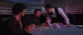 Movie still from “Carlito's Way” (1993), directed by Brian De Palma – A group of men sitting at a table with plates of food in front of them; Medium shot, Over the shoulder angle