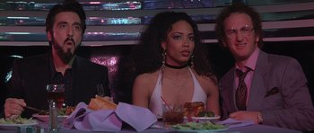 Movie still from “Carlito's Way” (1993), directed by Brian De Palma – A woman sitting at a table with a plate of food in front of her; Medium shot, Over the shoulder angle