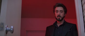 Movie still from “Carlito's Way” (1993), directed by Brian De Palma – A man in a black suit standing in front of a red wall; Close Up shot, Low angle