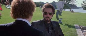 Movie still from “Carlito's Way” (1993), directed by Brian De Palma – A man in a suit and sunglasses talking to another man; Medium shot, Over the shoulder angle