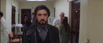Movie still from “Carlito's Way” (1993), directed by Brian De Palma – A man in a suit and tie standing in front of a group of people; Medium shot, Low angle
