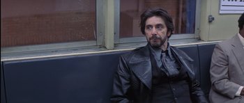 Movie still from “Carlito's Way” (1993), directed by Brian De Palma – A man sitting on a bench in front of a window; Medium shot, Over the shoulder angle