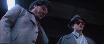 Movie still from “Carlito's Way” (1993), directed by Brian De Palma – A man in a suit and tie next to another man in a hat and jacket; Close Up shot, Low angle