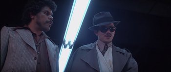 Movie still from “Carlito's Way” (1993), directed by Brian De Palma – A man wearing a hat and a coat and sunglasses; Medium shot, Low angle