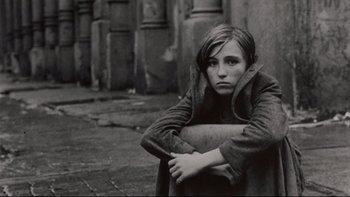 Movie still from “Days of Heaven” (1978), directed by Terrence Malick – A woman sitting on the ground with her arms crossed; Close Up shot, High angle