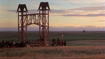 Movie still from “Days of Heaven” (1978), directed by Terrence Malick – A group of people sitting in a field under a structure; Extreme Wide shot, Low angle