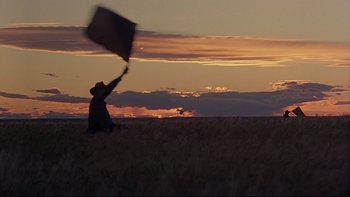 Movie still from “Days of Heaven” (1978), directed by Terrence Malick – A person flying a kite in a field at sunset; Extreme Wide shot, Low angle