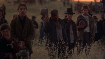 Movie still from “Days of Heaven” (1978), directed by Terrence Malick – A group of people standing in a field with hats on; Medium shot, Low angle