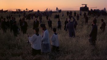 Movie still from “Days of Heaven” (1978), directed by Terrence Malick – A group of people standing in a field at sunset; Extreme Wide shot, High angle