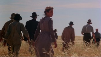 Movie still from “Days of Heaven” (1978), directed by Terrence Malick – A group of people walking through a field; Medium shot, Low angle