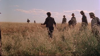 Movie still from “Days of Heaven” (1978), directed by Terrence Malick – A group of people standing in tall grass; Extreme Wide shot, Low angle