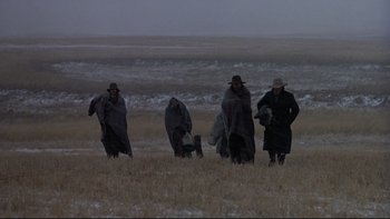 Movie still from “Days of Heaven” (1978), directed by Terrence Malick – A group of people walking across a dry grass field; Extreme Wide shot, High angle