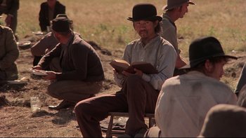 Movie still from “Days of Heaven” (1978), directed by Terrence Malick – A group of men sitting in a field reading books; Medium shot, Over the shoulder angle