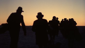 Movie still from “Days of Heaven” (1978), directed by Terrence Malick – A group of people walking across a beach at sunset; Wide shot, Low angle