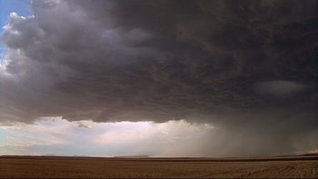 Movie still from “Days of Heaven” (1978), directed by Terrence Malick – Dark clouds loom over a field in the distance; Extreme Wide shot, Low angle
