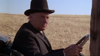Movie still from “Days of Heaven” (1978), directed by Terrence Malick – An older man in a suit and hat sitting in a field; Close Up shot, Low angle
