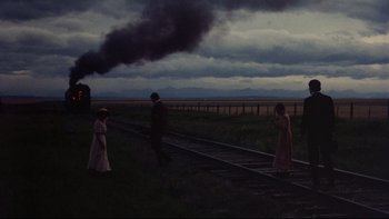 Movie still from “Days of Heaven” (1978), directed by Terrence Malick – A couple of people standing on top of a train track; Wide shot, High angle