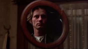 Movie still from “Days of Heaven” (1978), directed by Terrence Malick – A man looking into a round mirror in front of a wall; Close Up shot, Low angle
