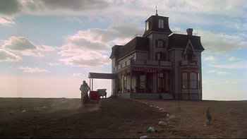 Movie still from “Days of Heaven” (1978), directed by Terrence Malick – A man standing in front of a large house; Extreme Wide shot, Low angle