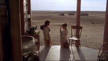 Movie still from “Days of Heaven” (1978), directed by Terrence Malick – Two women are standing on a porch looking out on a desert; Wide shot, Over the shoulder angle