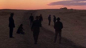 Movie still from “Days of Heaven” (1978), directed by Terrence Malick – A group of men standing on top of a dirt hill; Extreme Wide shot, High angle