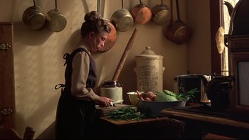Movie still from “Days of Heaven” (1978), directed by Terrence Malick – A woman in an old - fashioned kitchen preparing food; Medium shot, High angle