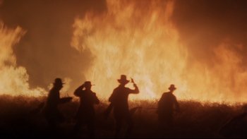Movie still from “Days of Heaven” (1978), directed by Terrence Malick – A group of men standing in front of a fire; Wide shot, Low angle