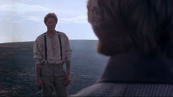 Movie still from “Days of Heaven” (1978), directed by Terrence Malick – A man standing on top of a hill holding a camera; Medium shot, Over the shoulder angle