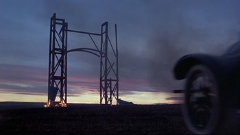 Movie still from “Days of Heaven” (1978), directed by Terrence Malick – A person walking in a field near a large structure; Extreme Wide shot, Low angle