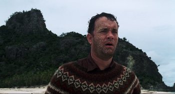 Movie still from “Cast Away” (2000), directed by Robert Zemeckis – A man with sand all over his face and body; Close Up shot, Low angle