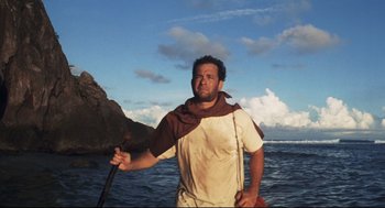 Movie still from “Cast Away” (2000), directed by Robert Zemeckis – A man standing in the water holding a spear; Medium shot, Low angle