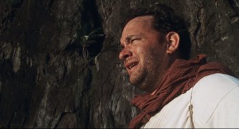 Movie still from “Cast Away” (2000), directed by Robert Zemeckis – A person wearing a scarf near a tree; Close Up shot, Low angle