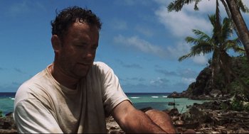 Movie still from “Cast Away” (2000), directed by Robert Zemeckis – A man sitting on the beach looking at the ocean; Medium shot, Low angle