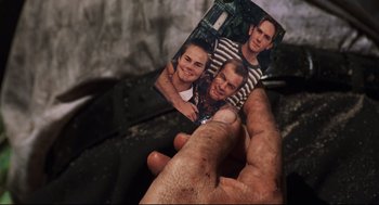Movie still from “Cast Away” (2000), directed by Robert Zemeckis – A man holding a picture of himself and two friends; Extreme Close Up shot, High angle