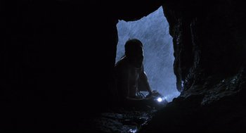 Movie still from “Cast Away” (2000), directed by Robert Zemeckis – A man in a cave with a flashlight; Wide shot, Low angle