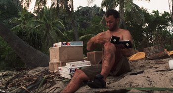 Movie still from “Cast Away” (2000), directed by Robert Zemeckis – A man sitting on the ground with boxes in front of him; Medium shot, Low angle